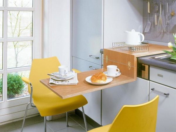 Самый бюджетный вариант стола для маленькой кухни – складная модель (по типу столиков в поездах). Конструкция изделия незатейлива и ее можно сделать самостоятельно по индивидуальным размерам