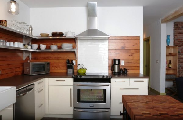 Оригинальный интерьер кухни с деревянным фартуком для защиты стен в зоне приготовления пищи